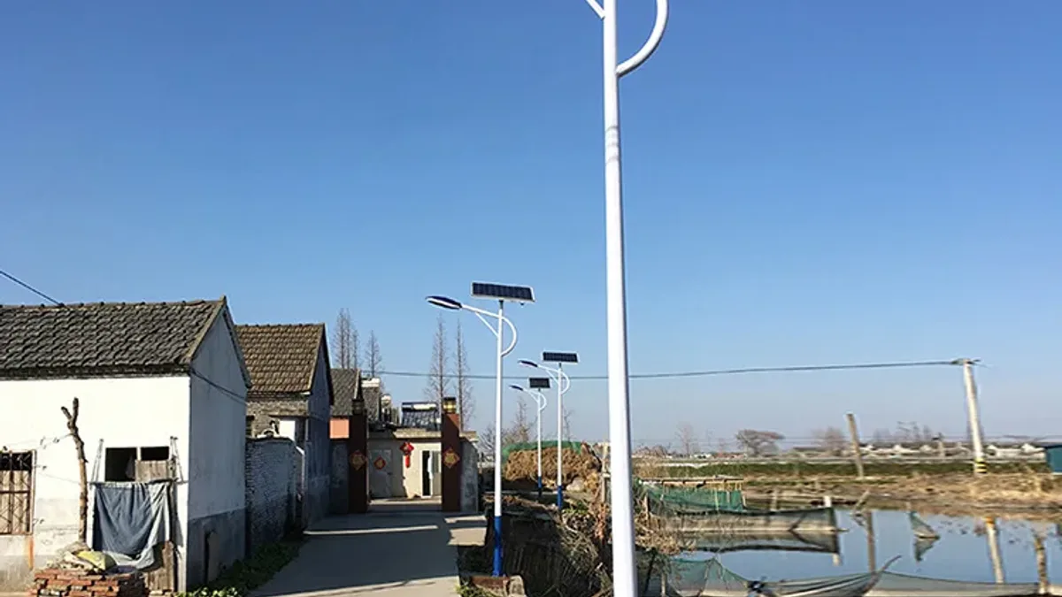 Solar street lights mounted on poles in a rural installation, each with a photovoltaic module on top of the luminaire